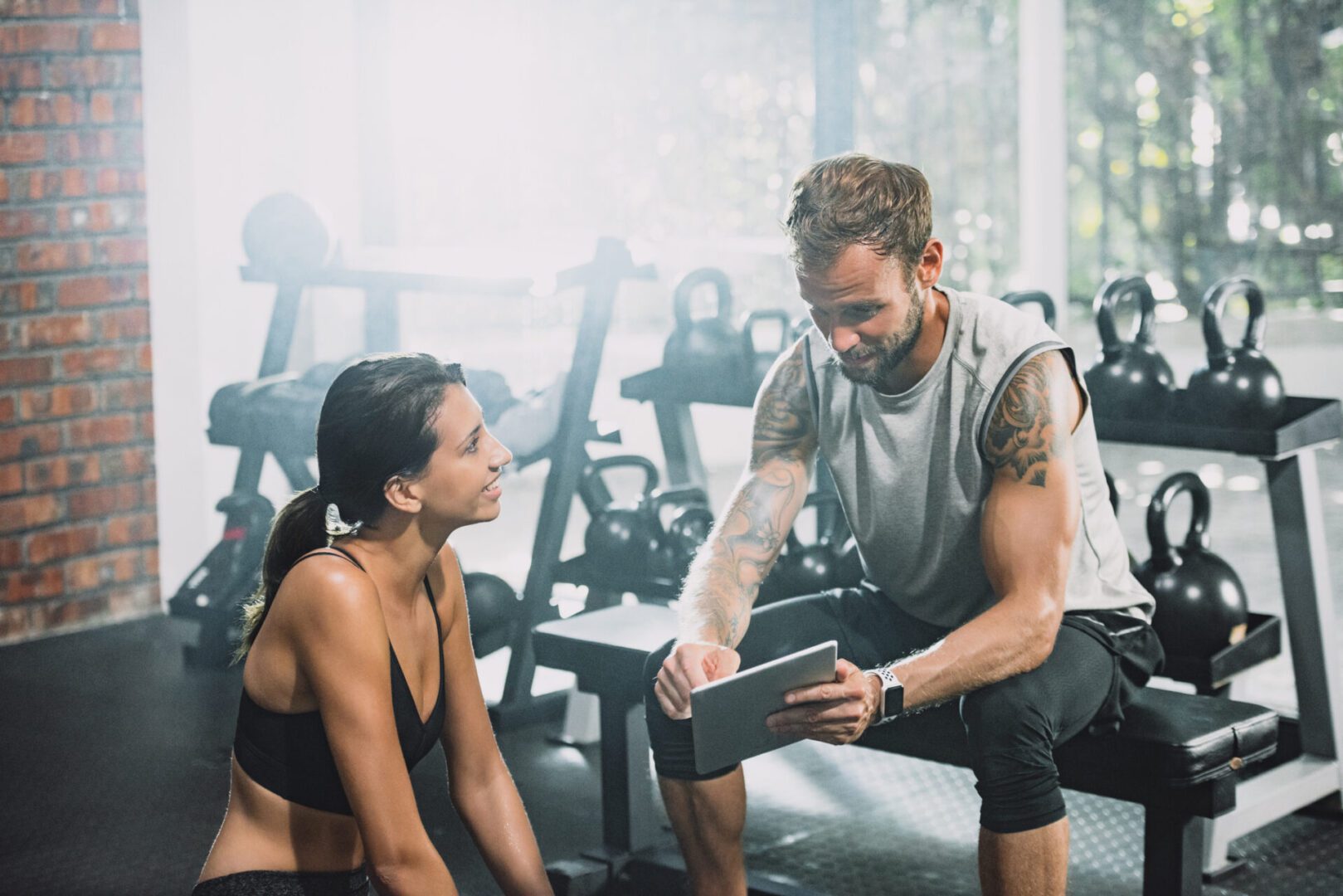 Man and woman discussing in gym setting.